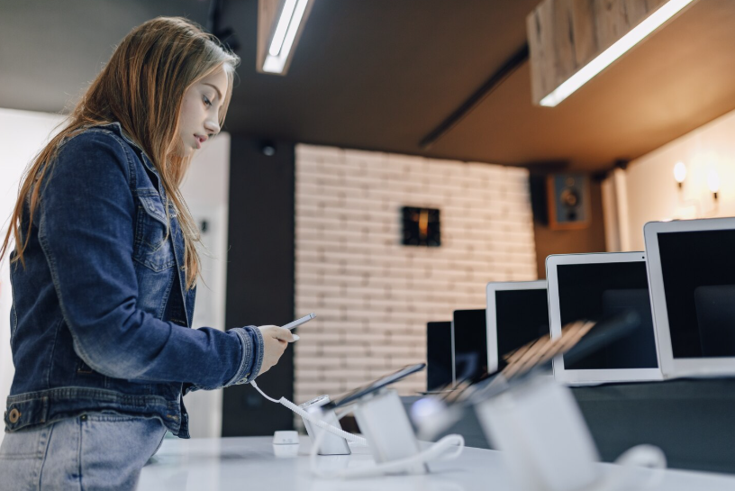 Shopper testing a mid-range smartphone in a store to compare features before making a purchase.