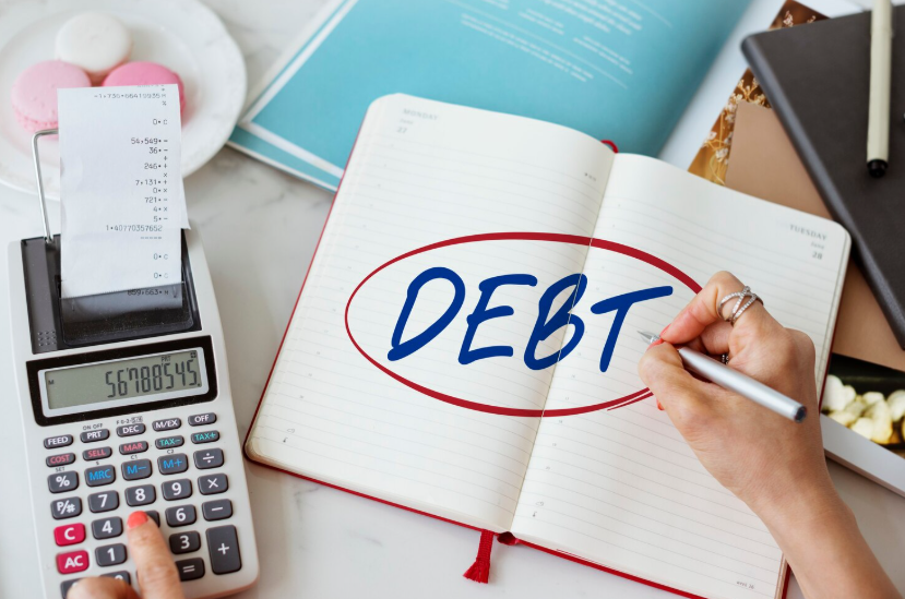Which debt should you pay off first shown with calculator and notebook highlighting debt planning.