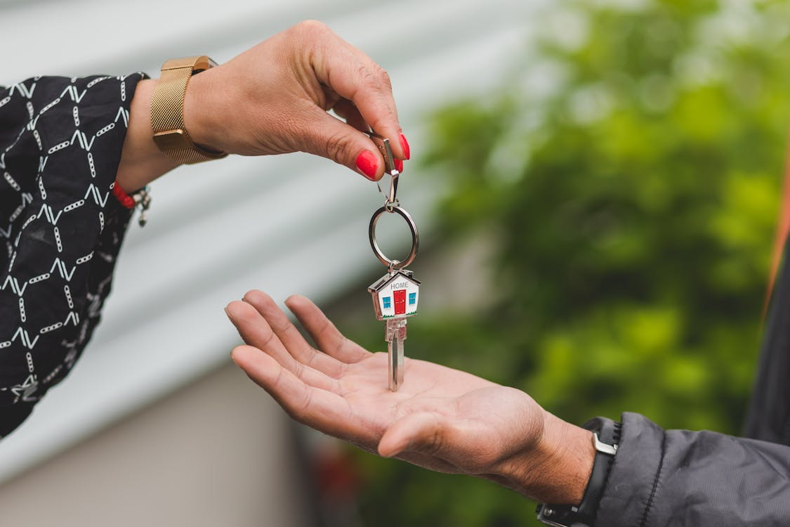 Renting vs buying decision shown by handing over house keys to tenant or homeowner.