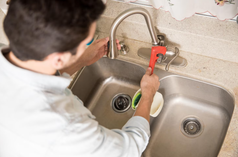 Easy DIY home repairs tightening a loose kitchen faucet with a wrench to prevent service costs.