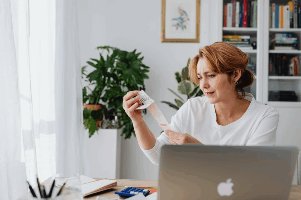 Woman reviewing household expenses during a weekly money audit while checking a long receipt.