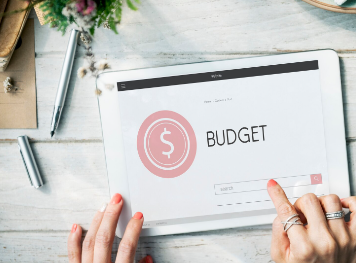 Person using a tablet to review budget planning with a modern budgeting dashboard.