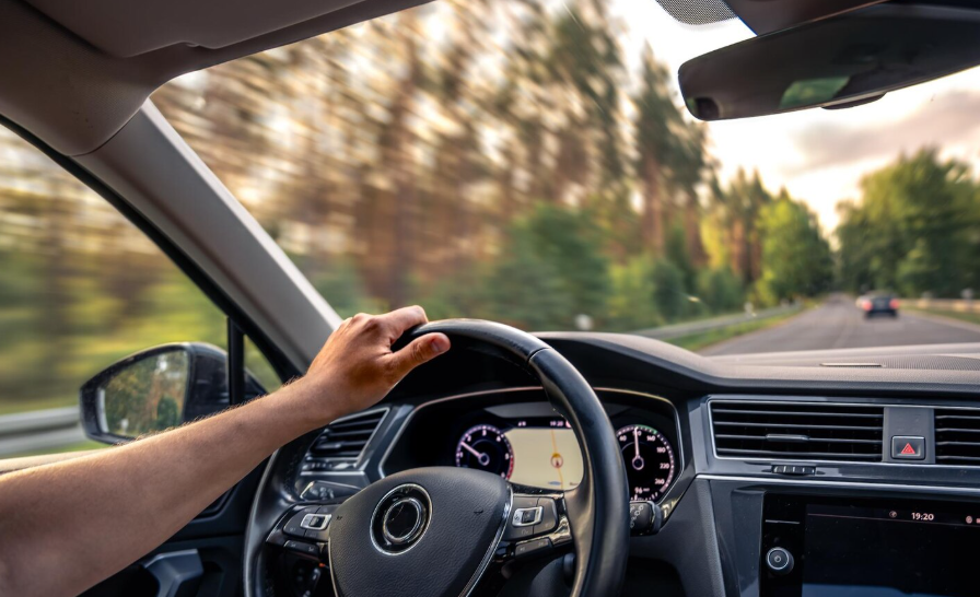Driver’s view behind the wheel showing real-world mileage and road wear for car replacement timing.
