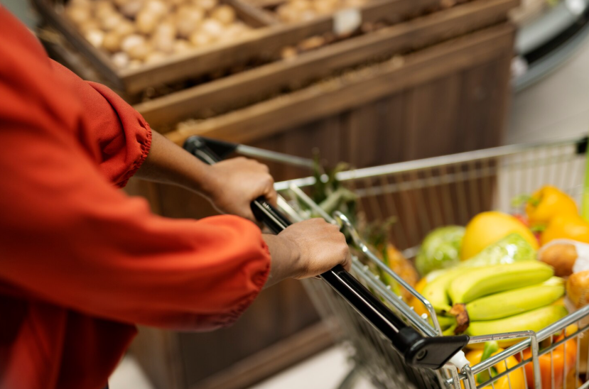 A grocery cart filled with fresh produce at the start of the grocery store triangle.
