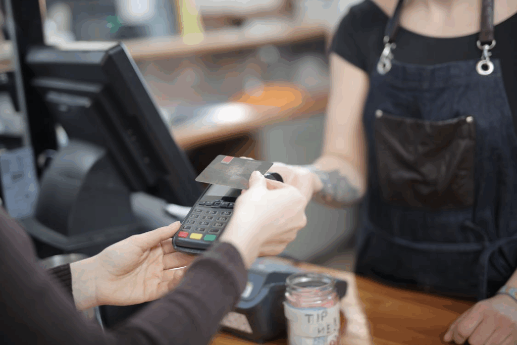 Customer tapping a credit card at checkout, illustrating how loyalty programs influence spending.