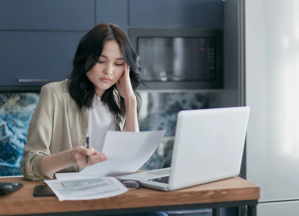 Woman reviewing monthly bills at home while planning what to cut and keep during a tight month.