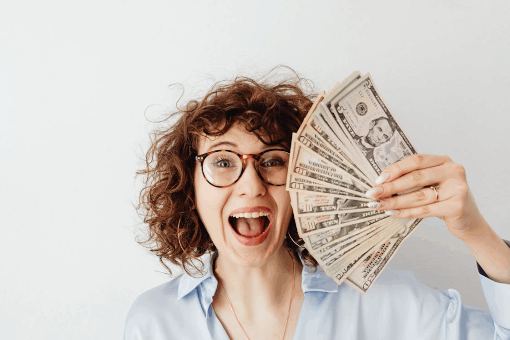Woman excitedly holding cash after receiving unexpected extra money or a financial windfall.